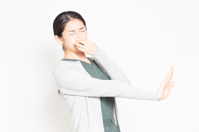 悪臭に困って鼻をつまんでいる女性